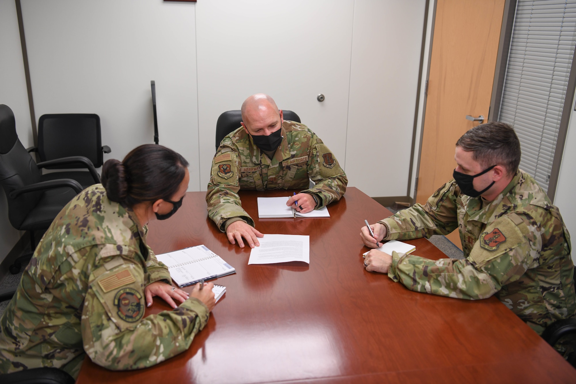 Three Airmen sit around a table to create a force development tool to enhance service member career plans.