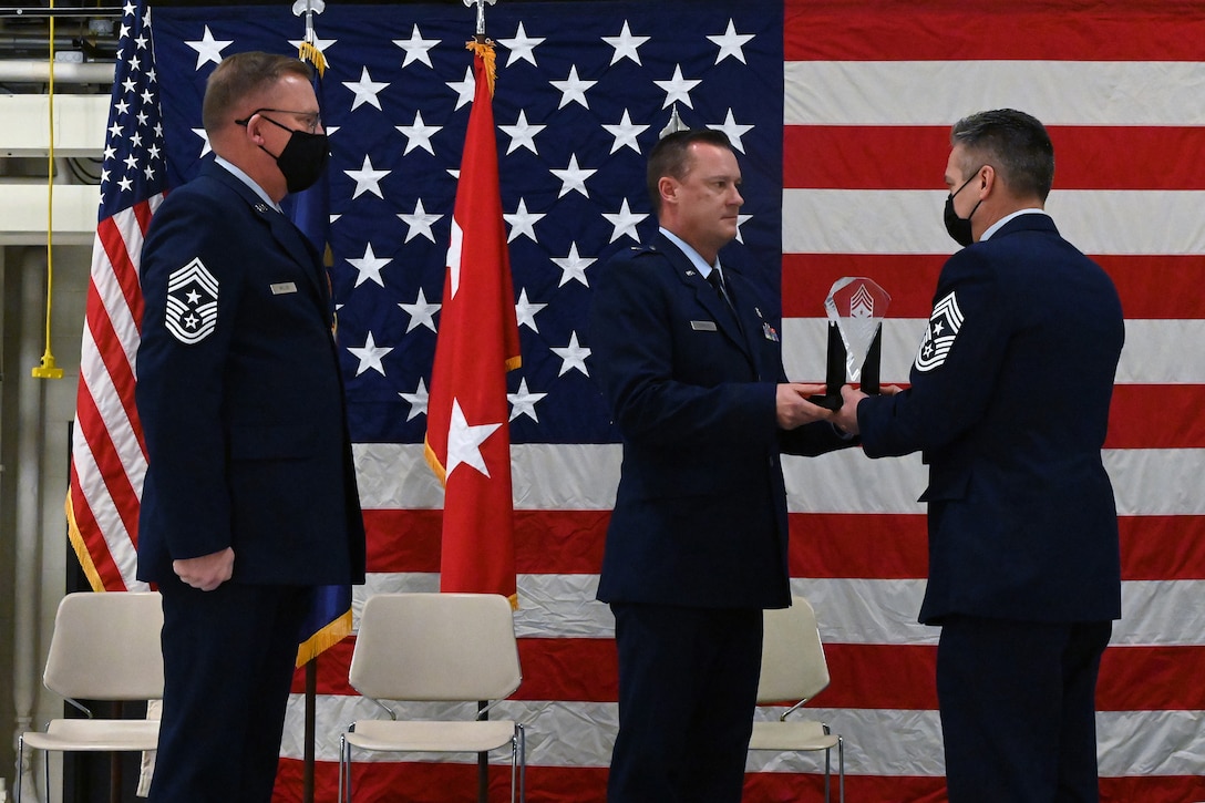 Brig. Gen. Robert Schulte, the North Dakota National Guard chief of staff for Air, presents a symbolic glass etching to Chief Master Sgt. Duane Kangas, right, as he assumes the position of State Command Chief during a change of responsibility ceremony at the North Dakota Air National Guard Base, Fargo, N.D., Dec. 5, 2020.
