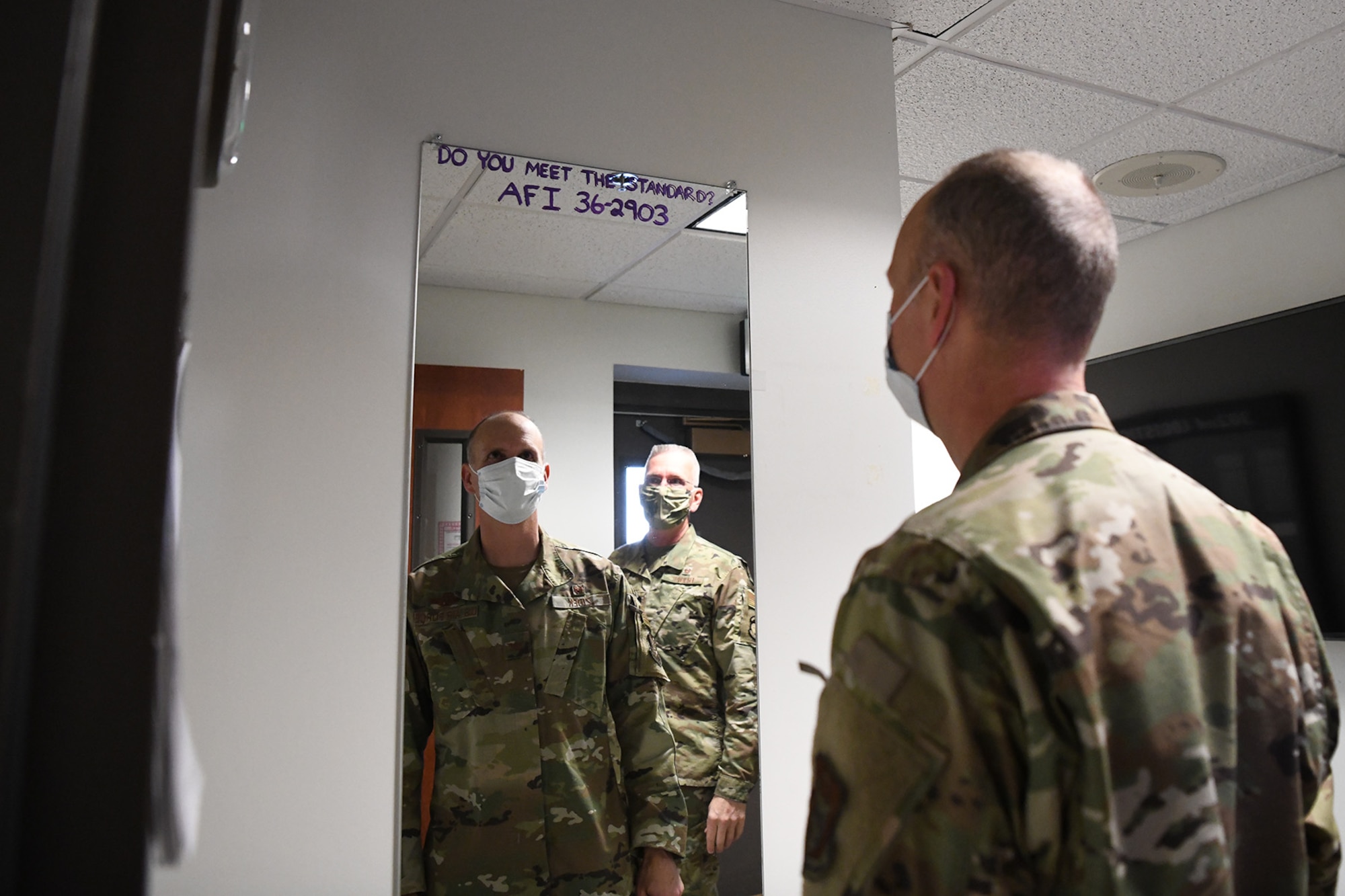 Col. Christopher Zidek, 302nd Airlift Wing commander, looks in a mirror at the entrance of the 302nd Logistics Readiness Squadron, to make sure he meets the Air Force Dress and Appearance standards during his visit to the squadron, Dec. 6, 2020, at Peterson-Schriever Garrison, Colorado.