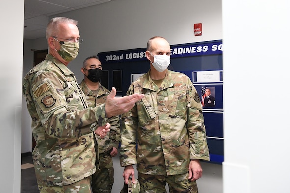 Lt. Col. Karl Fruendt (left), 302nd Logistics Readiness Squadron commander, shows the squadron white board to Col. Christopher Zidek (right), 302nd Airlift Wing commander, and Chief Master Sgt. Kahn Scalise (center), 302 AW command chief, during a squadron visit, Dec. 6, 2020, at Peterson-Schriever Garrison, Colorado