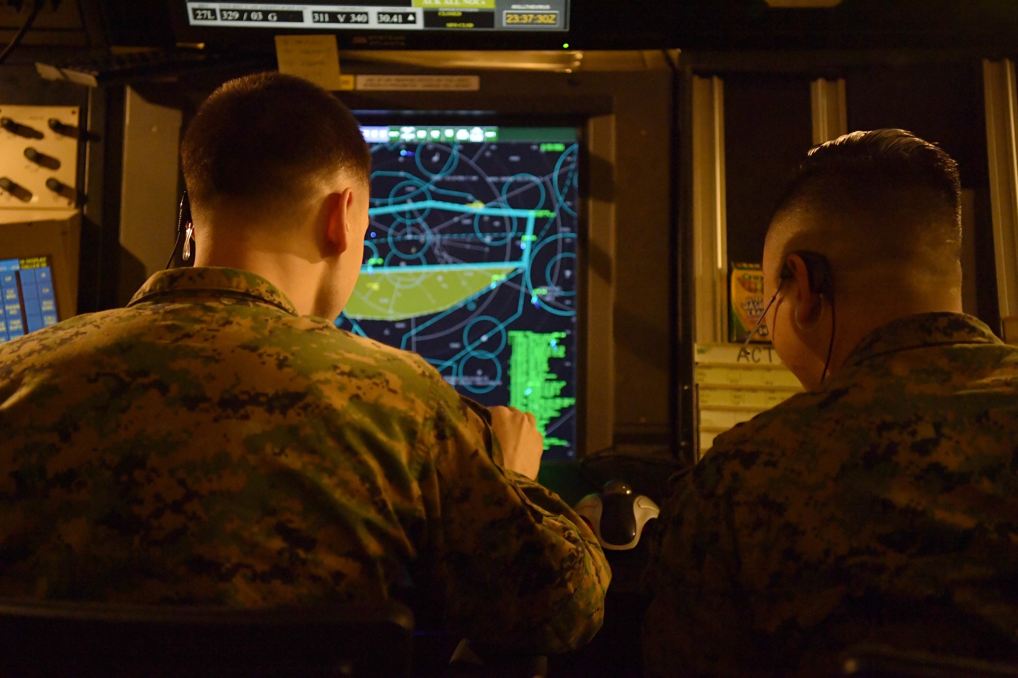 U.S. Marine Corps air traffic controllers Sgt. Adam Burse, Marine Corps Air Station (MCAS) Iwakuni, Japan, left, and Corporal William Chong, MCAS Futenma, Japan, examine an airspace radar during Radar Approach Control (RAPCON) operations at Osan Air Base, Republic of Korea, Dec. 3, 2020. The Pennsylvania natives paired as the first Marines to integrate into a multi-service ATC exchange program, where they are learning and operating Air Force Radar Approach Control (RAPCON) facility concepts to enhance safer flight line operations. (U.S. Air Force photo by Senior Airman Noah Sudolcan)