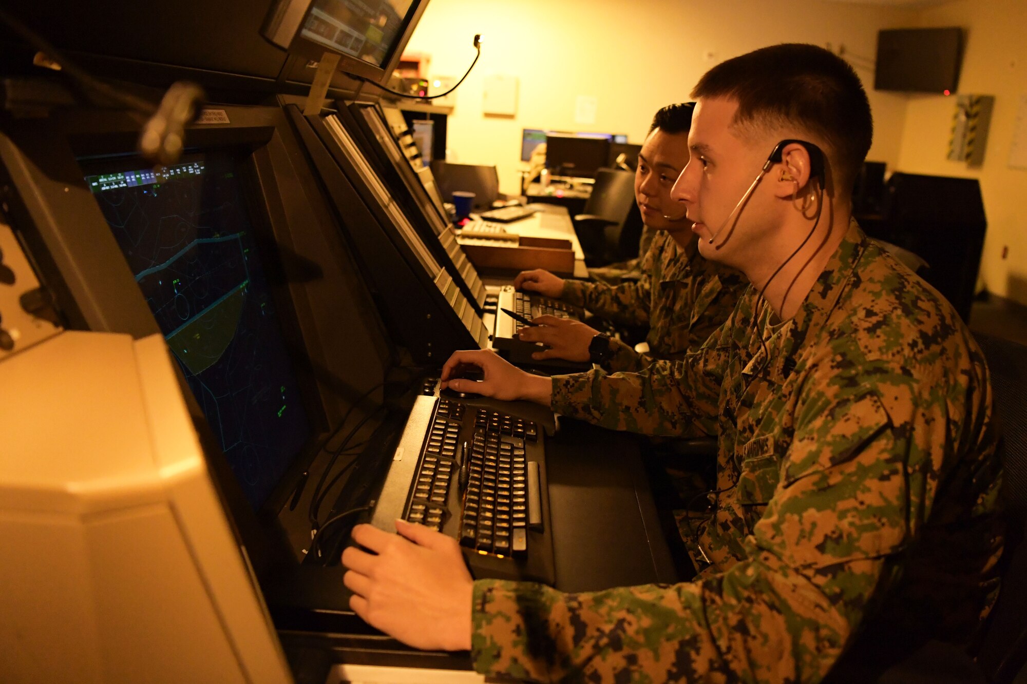U.S. Marine Corps air traffic controllers Sgt. Adam Burse, Marine Corps Air Station (MCAS) Iwakuni, Japan, front, and Corporal William Chong, MCAS Futenma, Japan, examine an airspace radar during Radar Approach Control (RAPCON) operations at Osan Air Base, Republic of Korea, Dec. 3, 2020. The Pennsylvania natives paired as the first Marines to integrate into a multi-service ATC exchange program, where they are learning and operating Air Force Radar Approach Control (RAPCON) facility concepts to enhance safer flight line operations. (U.S. Air Force photo by Senior Airman Noah Sudolcan)
