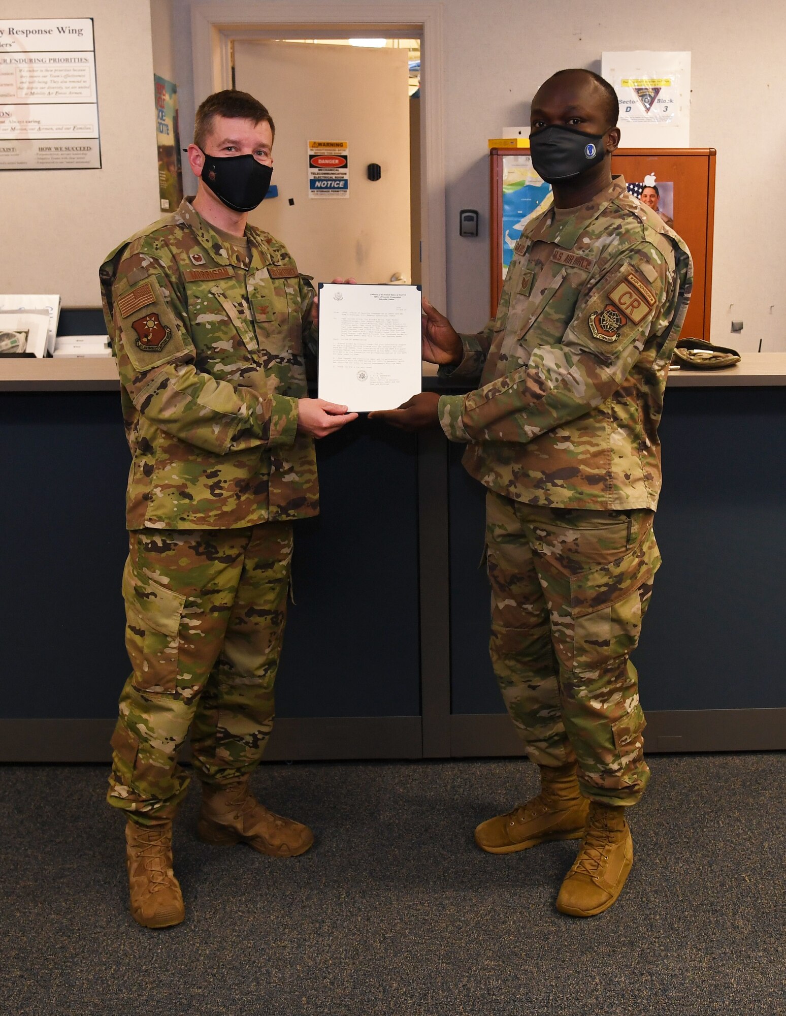 U.S. Air Force Col. Philip Morrison, 621st Air Mobility Advisory Group commander, presents with a letter of appreciation from the U.S. Embassy in Gabon to U.S. Air Force Tech. Sgt. DieuDonne Batawila, 818th Mobility Support Advisory Squadron language and culture air advisor, at Joint Base McGuire-Dix-Lakehurst, New Jersey, Nov. 3, 2020. Batawila was among 24 Language Enabled Airman Program scholars who volunteered to translate two training manuals for the Gabonese National Park Service Eco-guard Training Program. (U.S. Air Force photo by Tech. Sgt. Luther Mitchell Jr.)