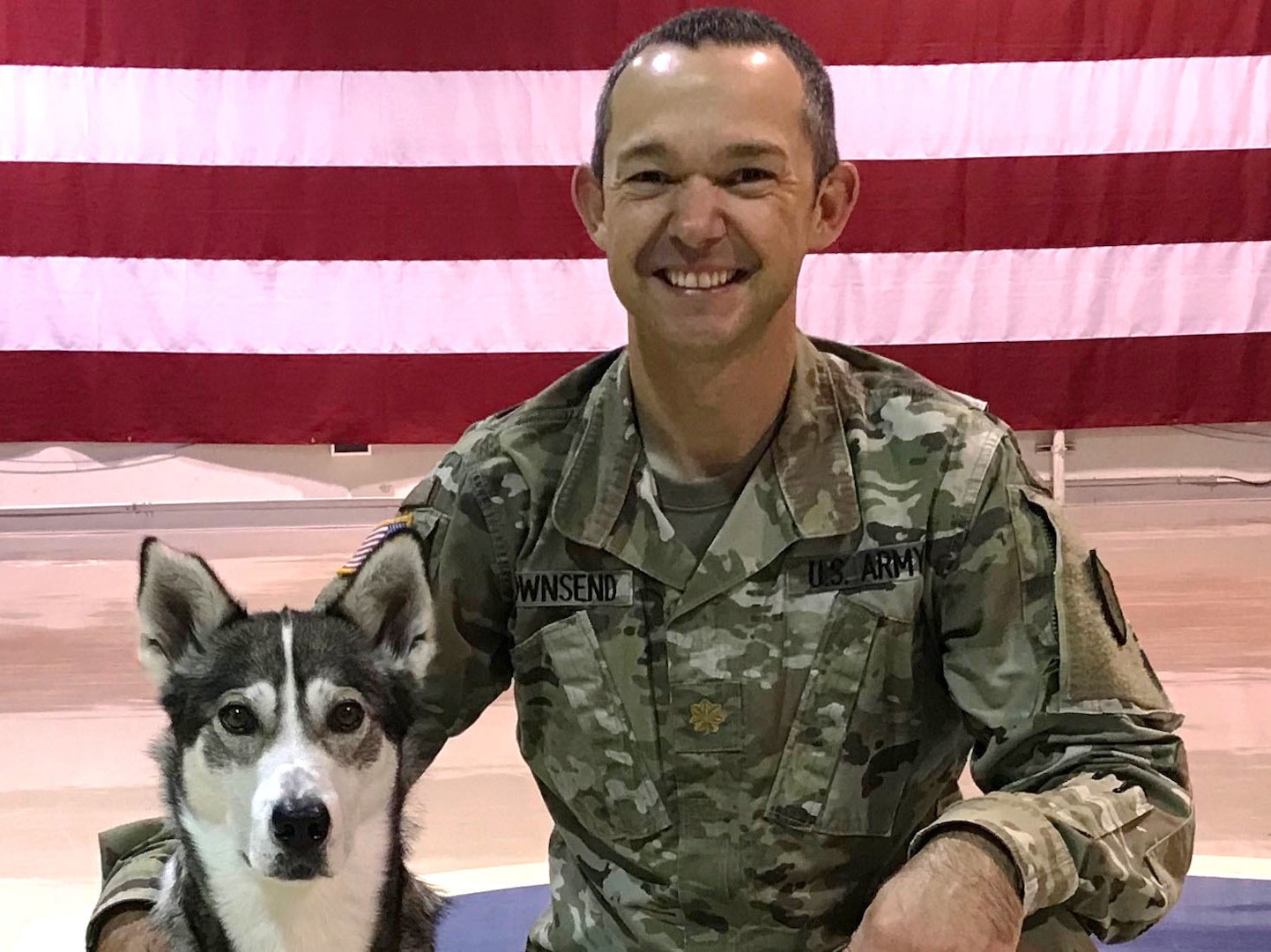 Maj. Troy Townsend, director of behavioral health, office of the state surgeon, New Hampshire Army National Guard, poses with therapy dog Cache Aug. 13, 2019. Cache, a 9-year-old retired sled dog, travels with Townsend across New Hampshire to meet Guard members.