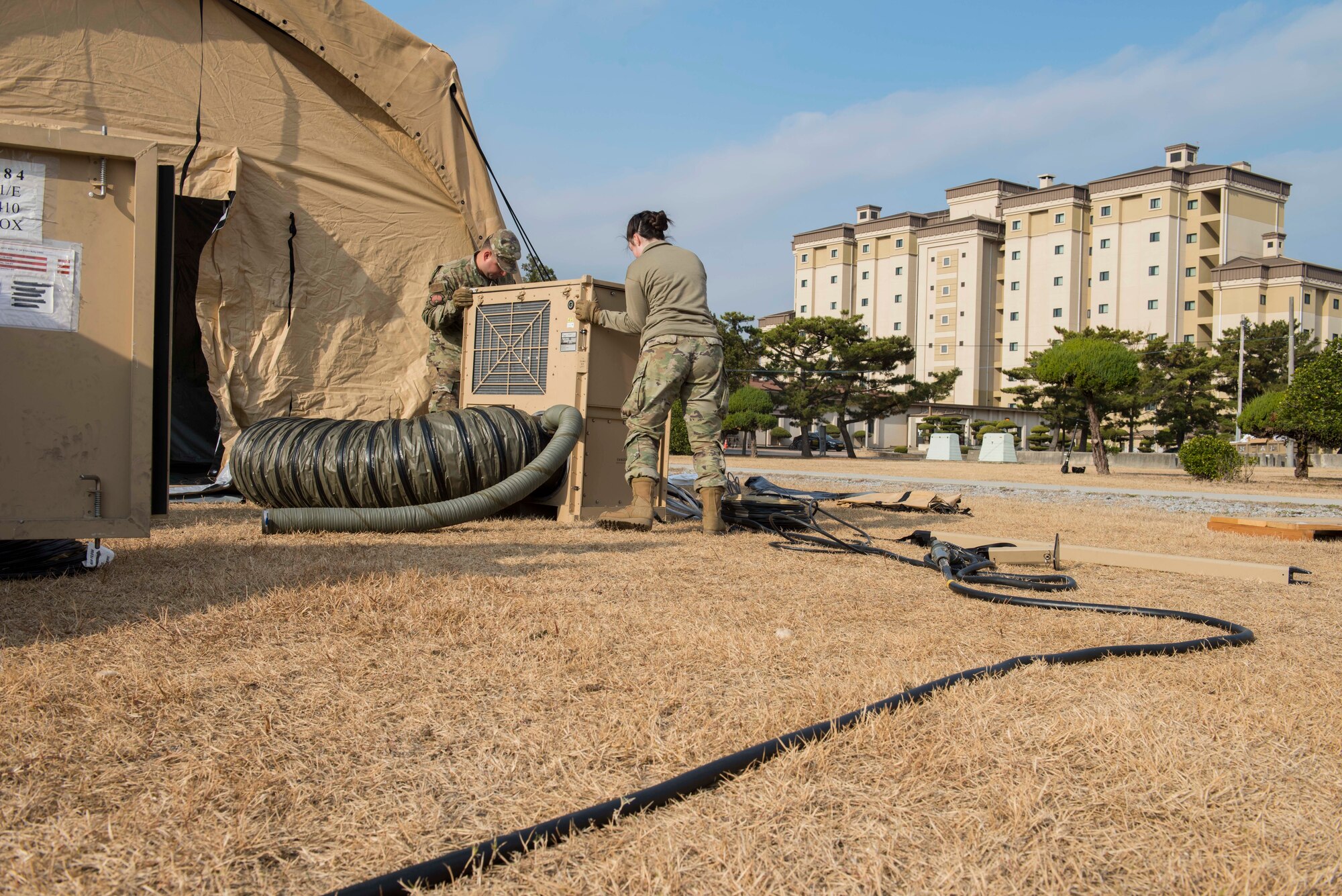 two Airmen moving an AC unit