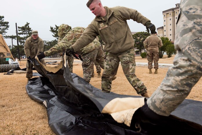 Airmen folding a tarp