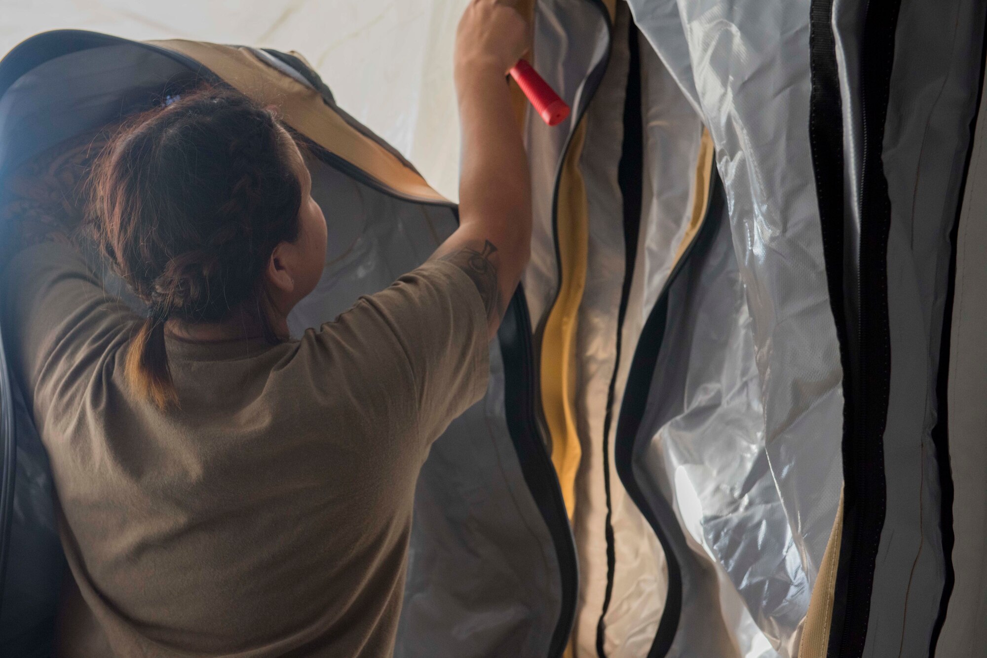 Airman zipping a tent door