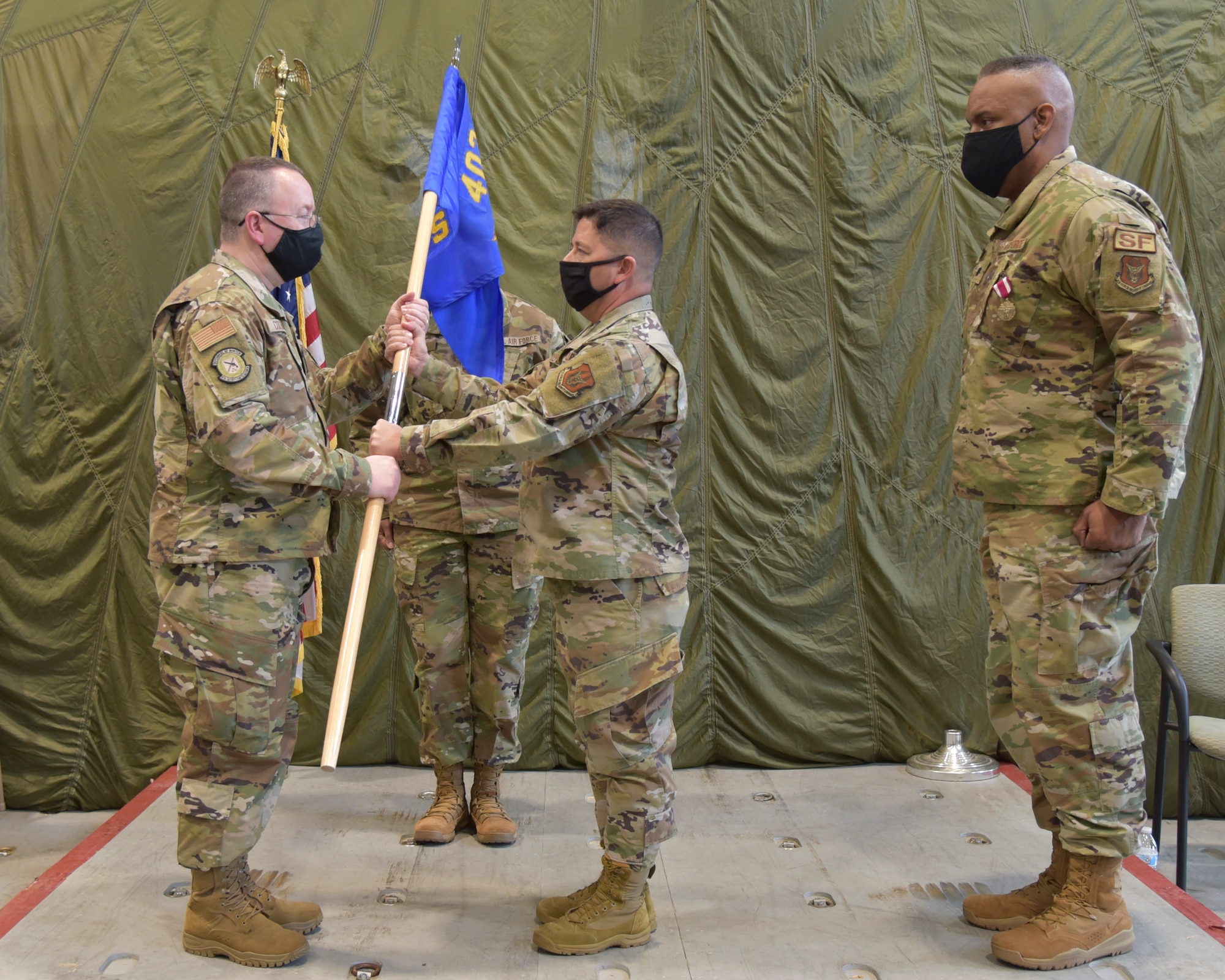 Lt. Col. Reginald G. Trujillo (center), 403rd Mission Support Group commander, hands the 403rd Security Forces Squadron guidon to Lt. Col. James A. Coleman (left), establishing him as the new commander of the 403rd SFS, during a ceremony in the 41st Aerial Port Squadron at Keesler Air Force Base, Mississippi, Dec. 5, 2020. (U.S. Air Force photo by Tech. Sgt. Michael Farrar)