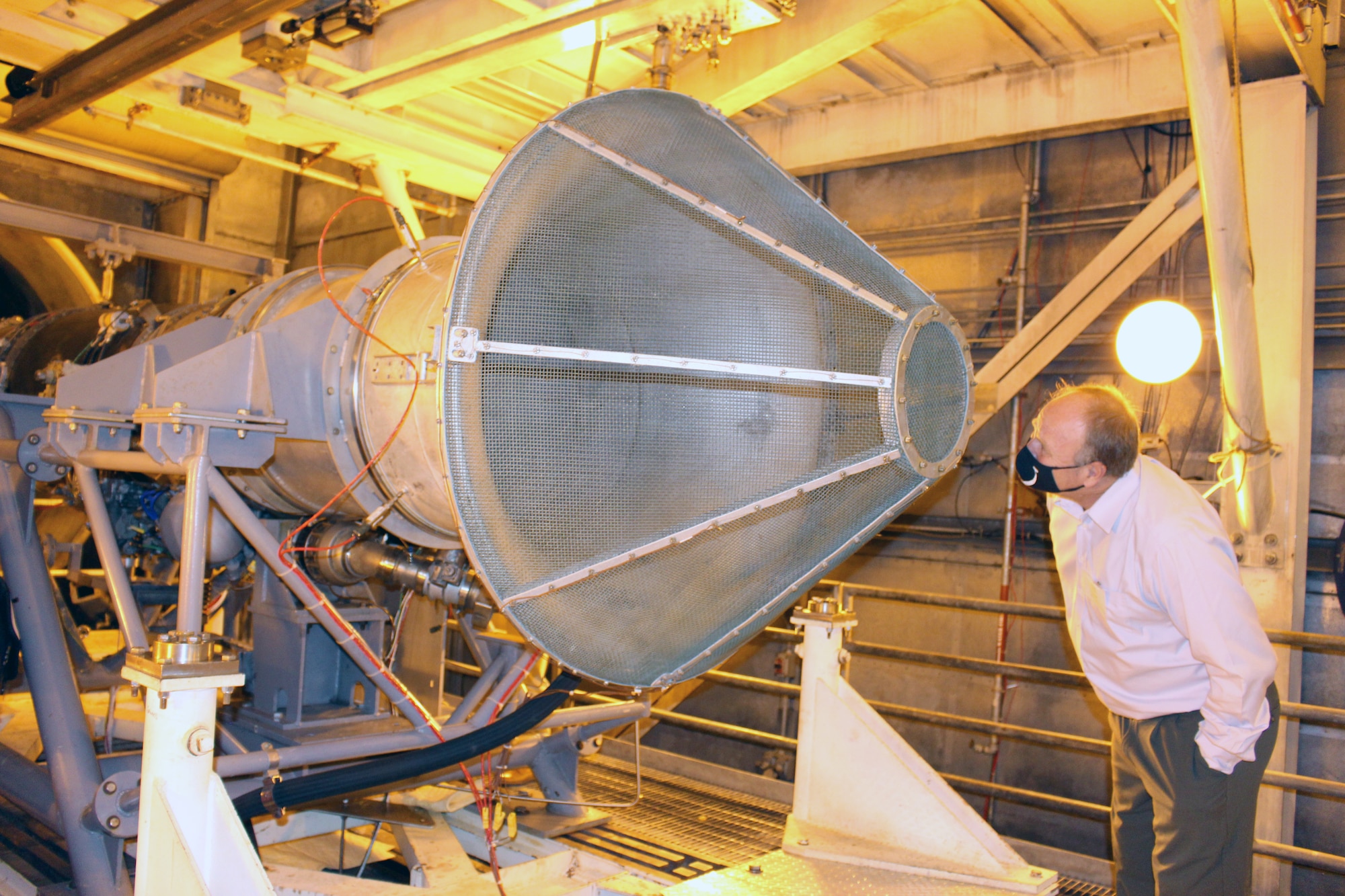 A member of the Propulsion Instrumentation Working Group views the F404 engine test stand in the Arnold Engineering Development Complex Sea Level 1 engine test cell at Arnold Air Force Base, Tenn., Oct. 28, 2020. The PIWG members visited Arnold to view the test facility and discuss how the test stand will be used to help mature new turbine engine instrumentation. (U.S. Air Force Photo by Deidre Moon)