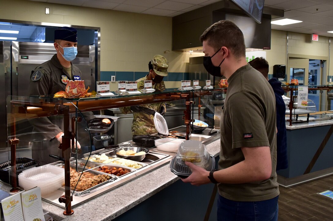 Col. Kurt Helphinstine, 4th Fighter Wing commander (left), serves food to Airman 1st Class Samuel Wenke, 4th Component Maintenance Squadron egress systems technician, during the Thanksgiving Day meal at Seymour Johnson Air Force Base,