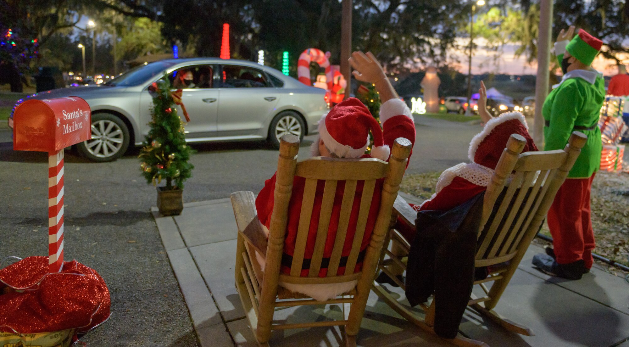 Santa Claus, Mrs. Claus and an elf wave to Keesler families as they drive by during Keesler's annual Christmas in the Park drive-thru celebration at Marina Park at Keesler Air Force Base, Mississippi, Dec. 4, 2020. The celebration, hosted by Outdoor Recreation, included light displays, hot chocolate and letters to Santa. (U.S. Air Force photo by Andre' Askew)