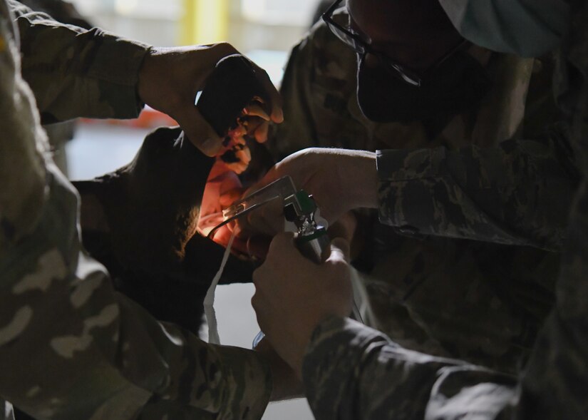 A 316th Medical Group member is guided through a simulated intubation procedure on K-9 Disel, a decoy dog used for training purposes, by U.S. Army Capt. Alexandra Bufford, course instructor and veterinarian at Ft. Belvoir, Va., during a Canine Tactical Combat Casualty Care Course, a training course designed to teach medical professionals how to aid wounded MWDs in deployed conditions, at Malcolm Grow Medical Clinics and Surgery Center at Joint Base Andrews, Md., Nov. 12, 2020.