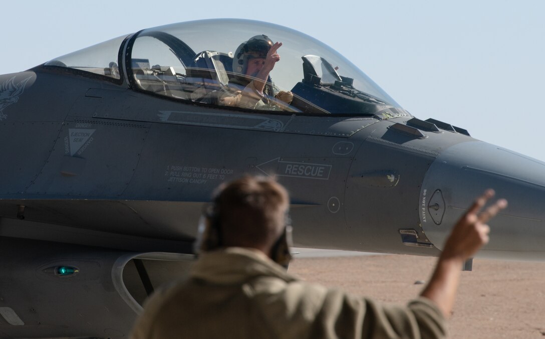 Capt. Elliot, a pilot assigned to the 77th Expeditionary Fighter Squadron, shows the 77th EFS hand sign to a 77th Fighter Generation Squadron maintainer while taxiing along the runway Dec. 1, 2020, at King Faisal Air Base, Kingdom of Saudi Arabia.