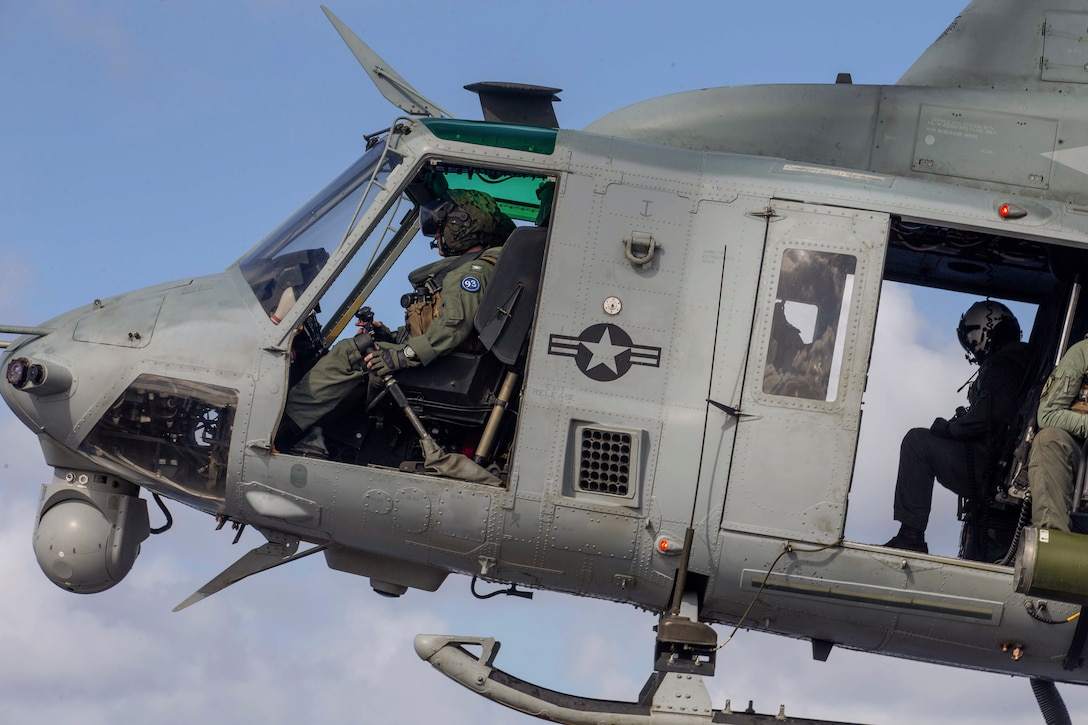 Service members fly in a helicopter.