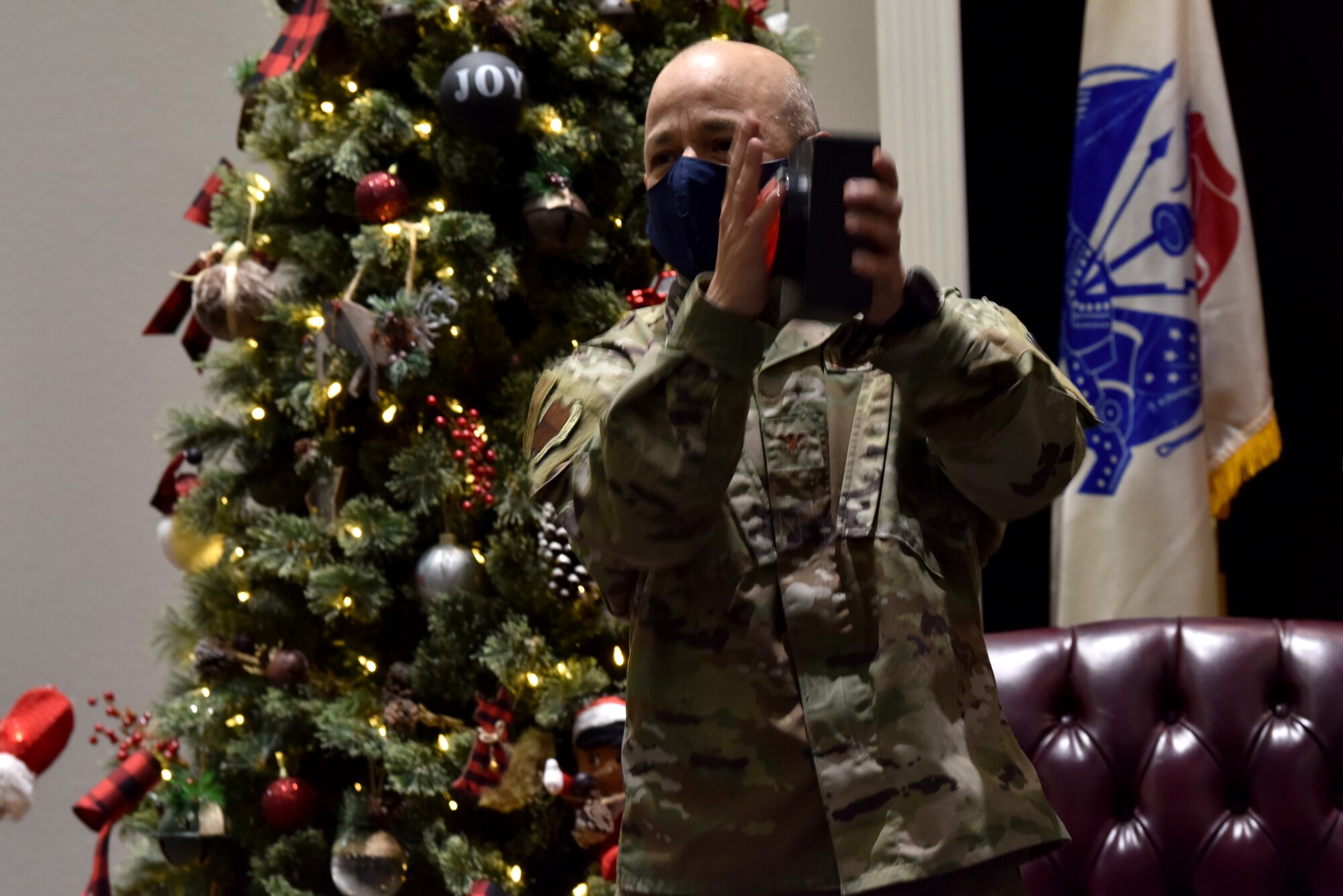 U.S. Air Force Col. Andres Nazario, 17th Training Wing commander, pushes the button to remotely light the Christmas tree at the Parade Field while standing in the Event Center on Goodfellow Air Force Base, Texas, Dec. 4, 2020. The lighting ceremony was held virtually to maintain tradition but abide by Centers for Disease Control and Prevention guidelines. (U.S. Air Force photo by Staff Sgt. Seraiah Wolf.)