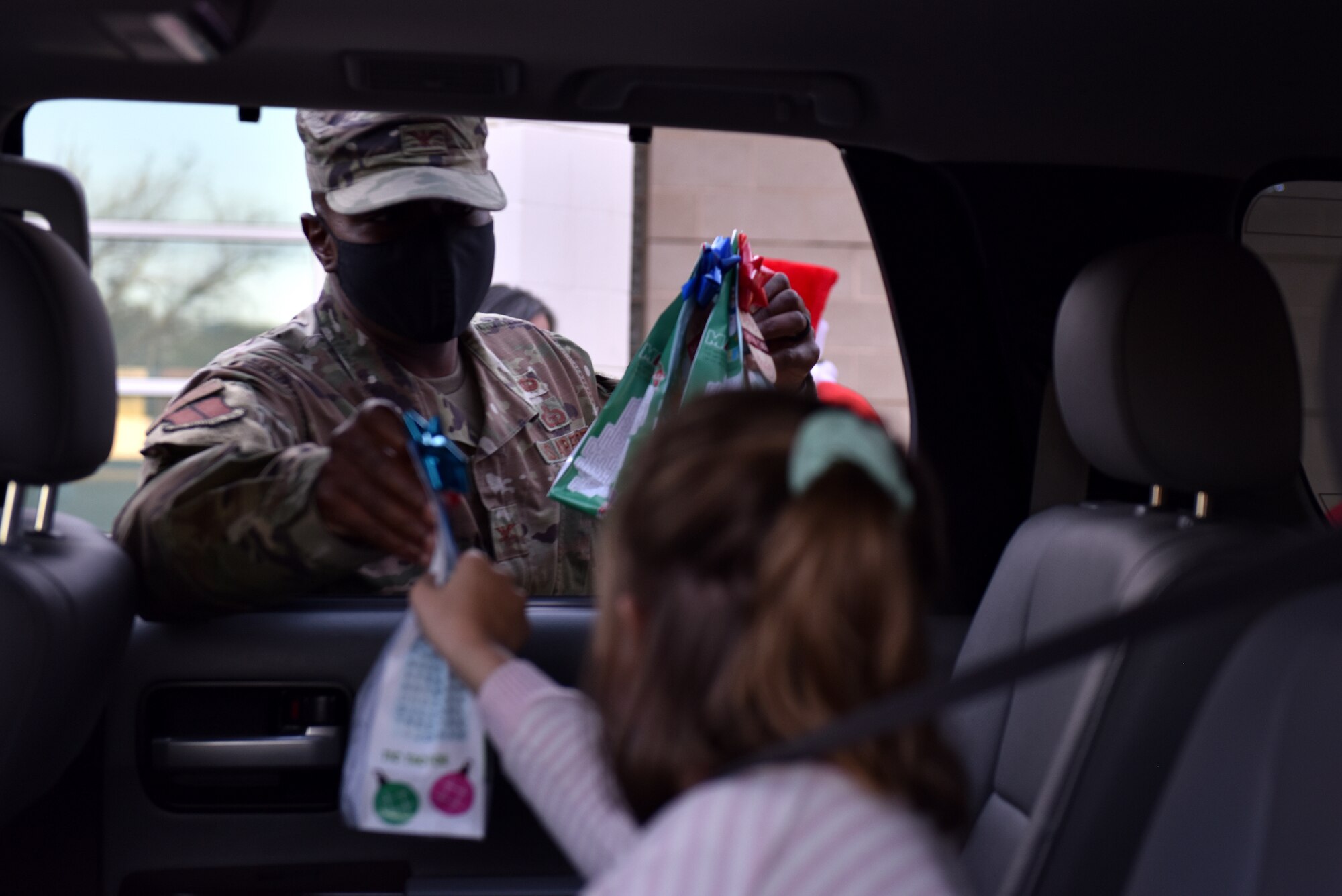 U.S. Air Force Col. James Finlayson, 17th Training Wing vice commander, hands a child a goody bag at the drive through craft pick-up during the virtual Christmas tree lighting ceremony in front of the Event Center on Goodfellow Air Force Base, Texas, Dec. 4, 2020. The goody bags were filled with candy, a Christmas ornament and craft supplies. (U.S. Air Force photo by Staff Sgt. Seraiah Wolf)