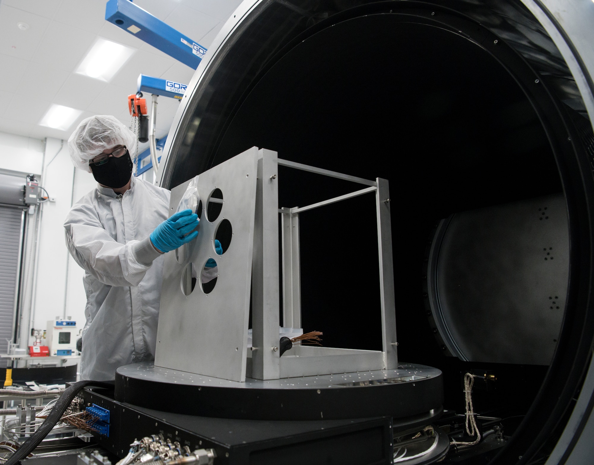 Eric D'Ambro, a test operations engineer, holds a material sample next to the frame that holds it in a Space Asset Resilience thermal vacuum chamber, Aug. 3, 2020, at Arnold Air Force Base, Tenn. The chamber can test the resiliency of materials and space systems under accurately simulated space conditions and natural threats. (U.S. Air Force photo by Jill Pickett)