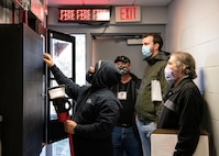 Photo of four people looking at a fire suppression panel