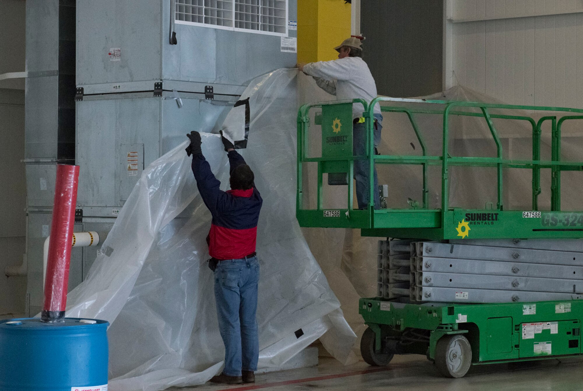 Photo of two workers putting plastic sheets against a wall