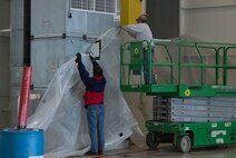 Photo of two workers putting plastic sheets against a wall