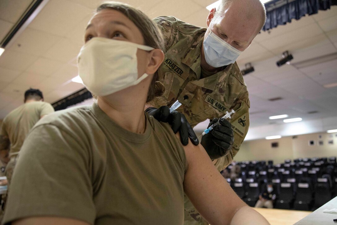A female officer receives a vaccine.