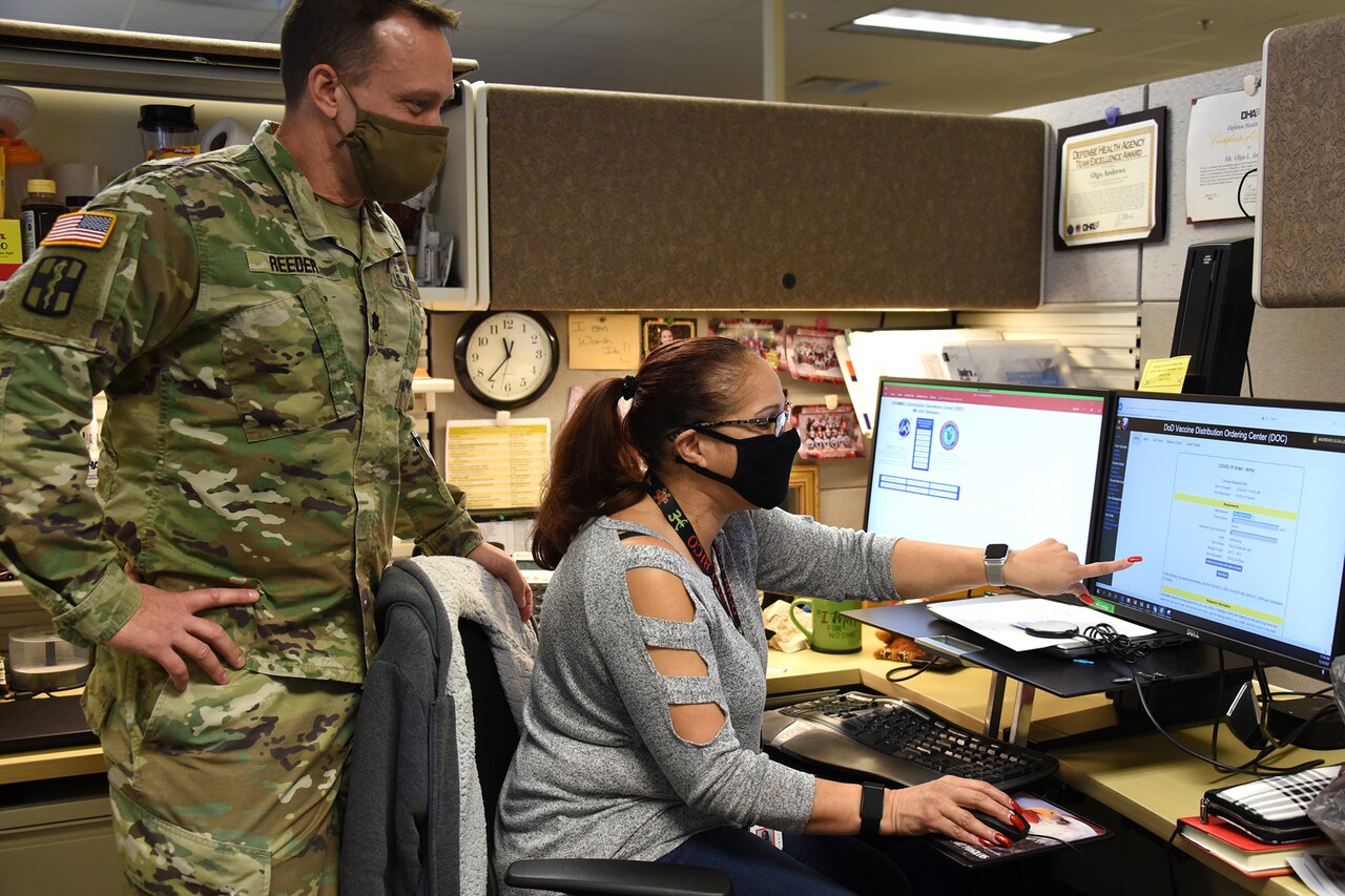 Two people look at a computer screen to make updates.