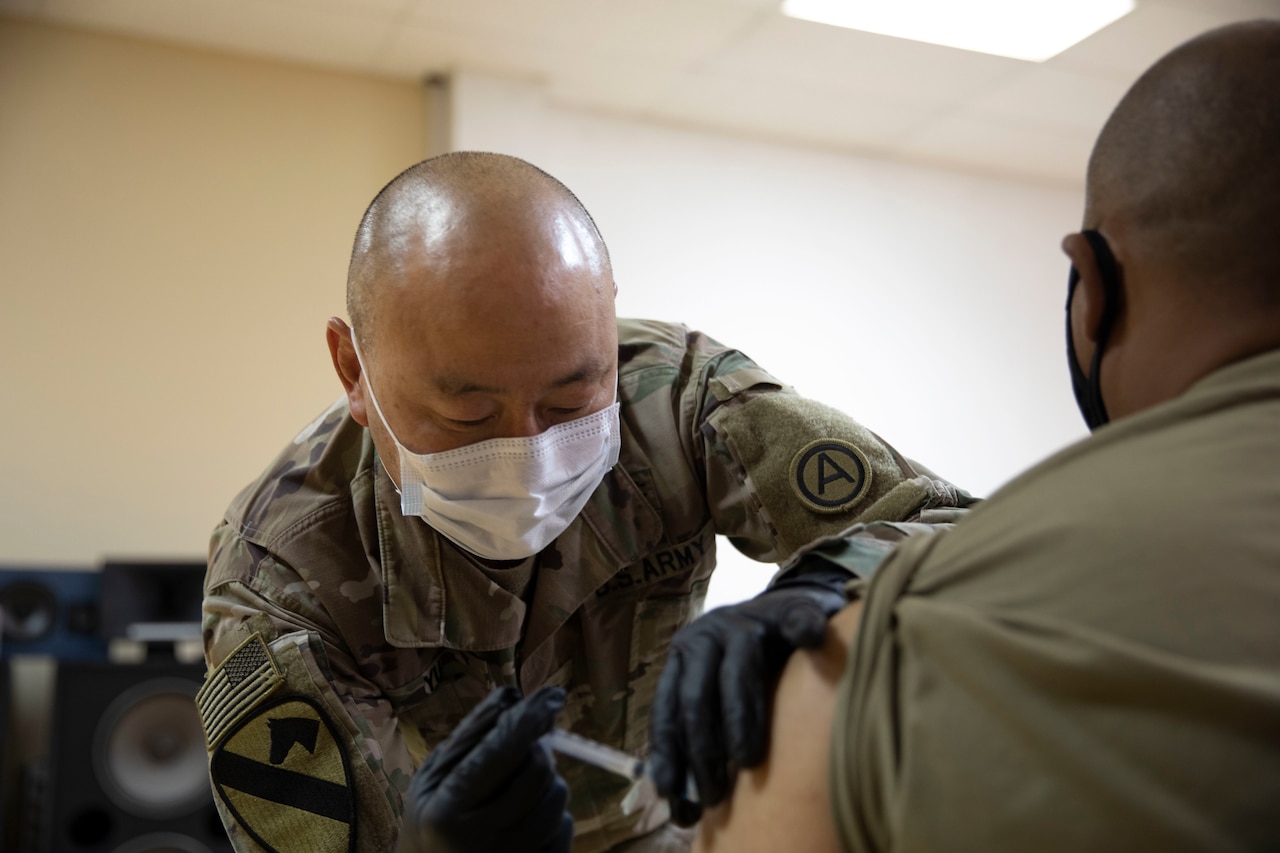 A soldier vaccinates another soldier.