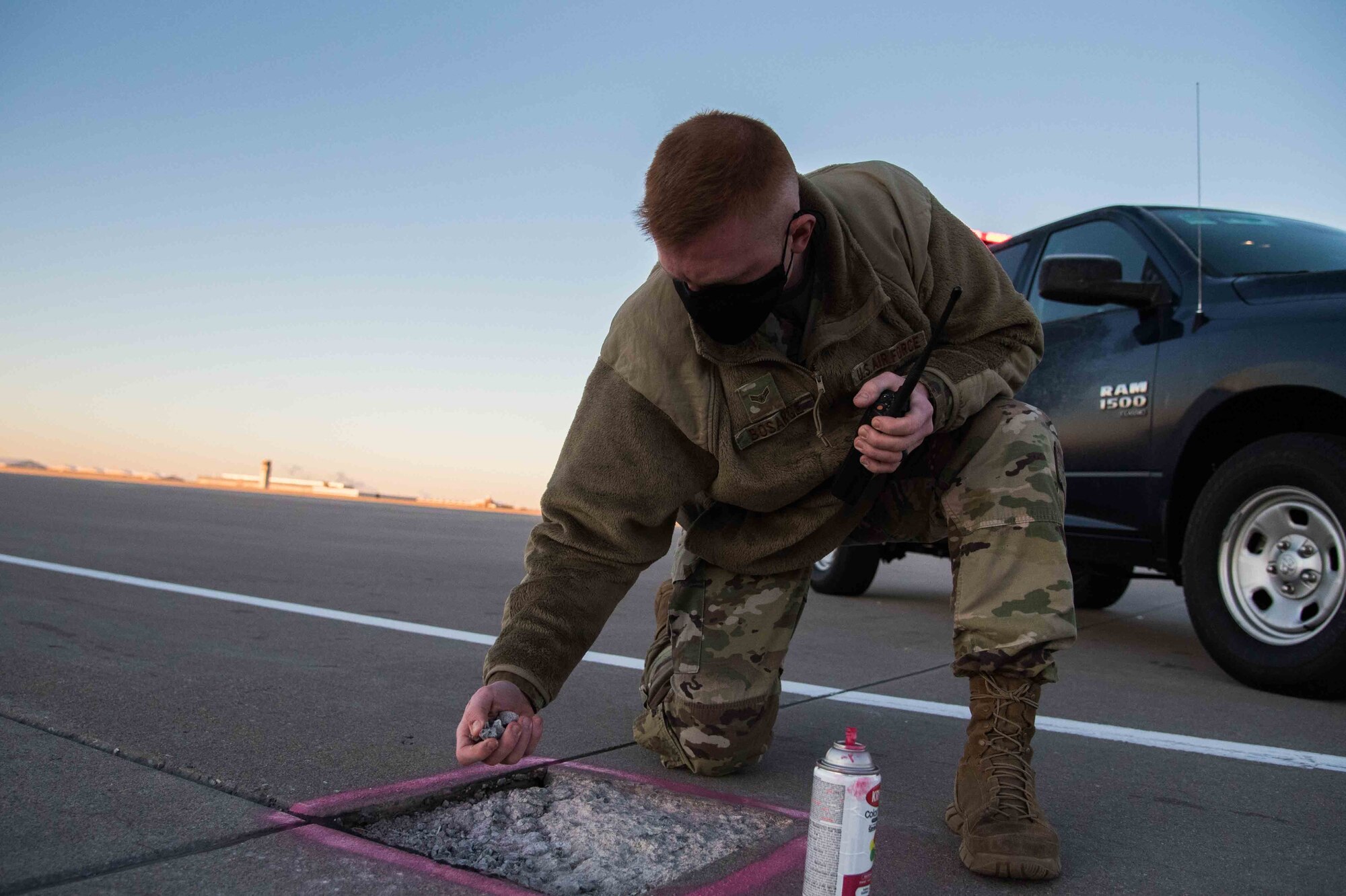 Airman 1st Class Douglas Bosarge, 22nd Operations Support Squadron airfield management journeyman, picks up foreign object debris on the flightline Dec. 4, 2020, at McConnell Air Force Base, Kansas. The airfield management team is required to conduct at least one visual inspections daily to prevent any hazards during aircraft operations. (U.S. Air Force photo by Senior Airman Alexi Bosarge)