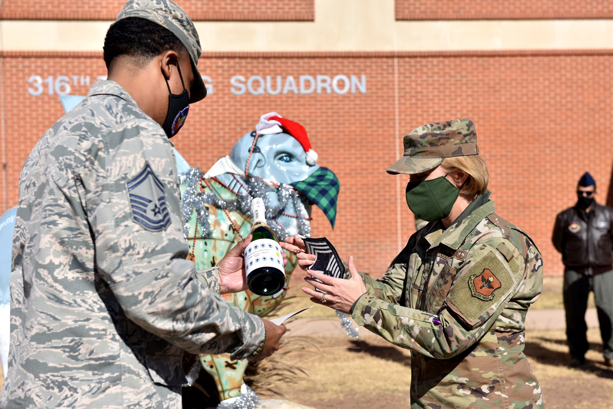 U.S. Air Force Chief Master Sgt. Casy Boomershine, 17th Training Wing command chief, presents Chief Master Sgt. select Aaron Shirley, 316th Training Squadron superintendent, with a gift commemorating earning his stripe in front of the 316th TRS on Goodfellow Air Force Base, Texas, Dec. 4, 2020. Less than 1 percent of enlisted are selected to become chief master sergeants. (U.S. Air Force photo by Staff Sgt. Seraiah Wolf)