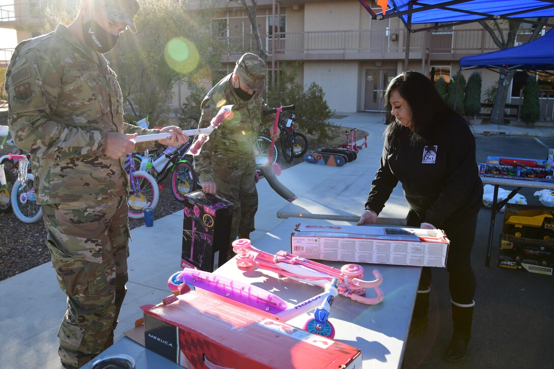 Col. Sean Carpenter, 926 Wing commander, Chief Master Sgt. Jeffery Scott, 926 WG command chief, and Kimmy McDaniel, non-profit director, help to build scooters and display toys for the Airmen and Family Readiness Operation Holiday Hope event, Dec. 5, 2020, Nellis Air Force Base, Nev. (U.S. Air Force Photo by Staff Sgt. Paige Yenke)