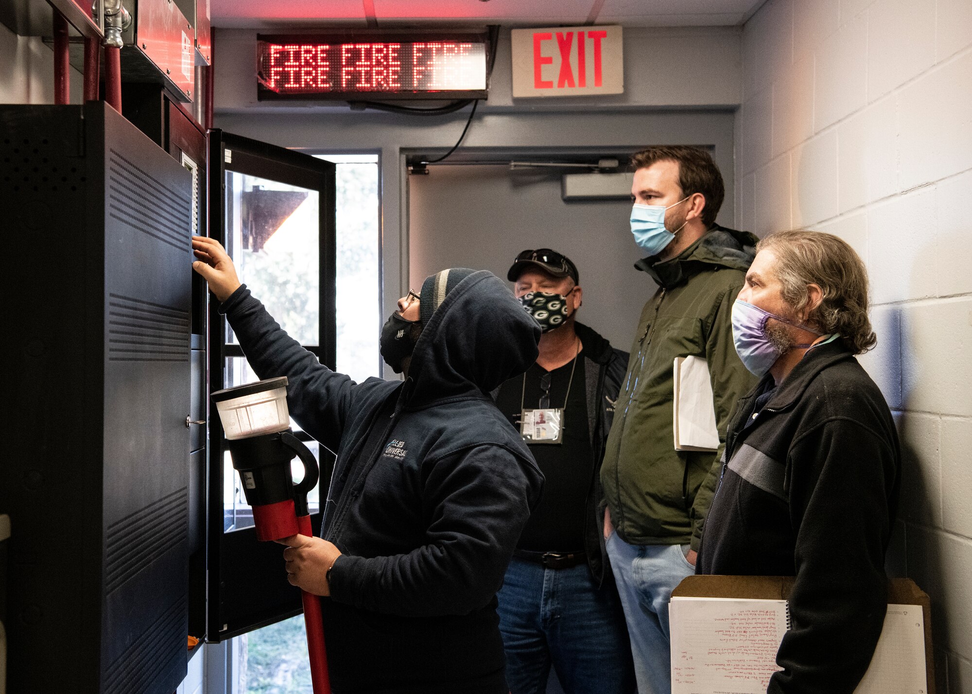 Photo of four people looking at a fire suppression panel