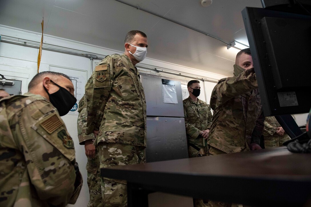 Lt. Gen. Greg Guillot, 9th Air Force (Air Forces Central) commander, and Chief Master Sgt. John Storms, 9th AF (AFCENT) command chief, listen to a brief by Tech. Sgt. Skylar Rudy, 387th Expeditionary Security Forces Squadron tactical automated security system and counter-small unmanned aerial system program manager, at Cargo City, Kuwait, Dec. 4, 2020. Guillot coined Rudy and other Airmen during the visit for their exceptional performance. (U.S. Air Force photo by Staff Sgt. Kenneth Boyton)