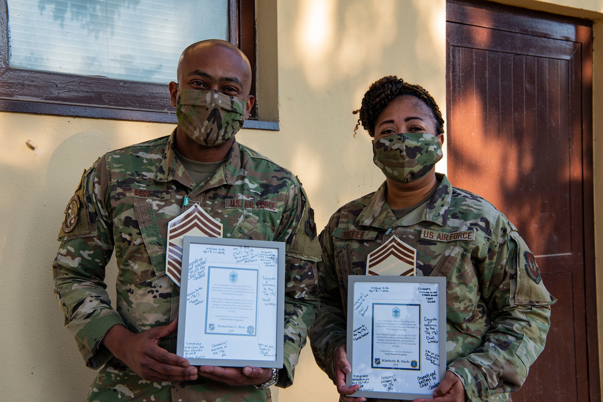 Photo of two airmen, holding promotion plaques