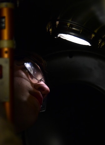 An Airman checks bolts on a fuel tank.
