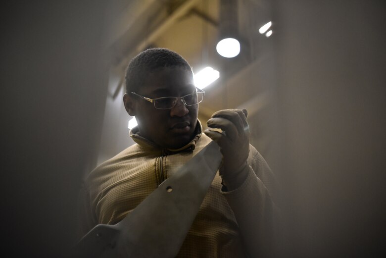 An Airman inspecting a fuel tank part.