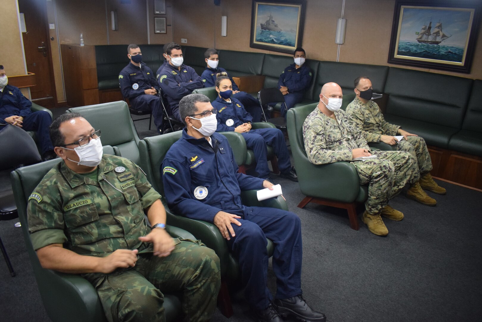Military personnel listen to a briefing.