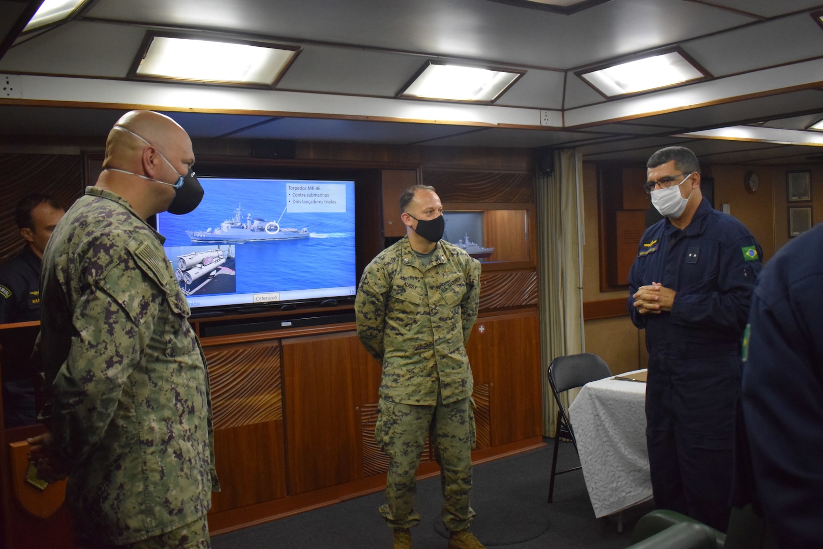 Military personnel listen to a briefing.