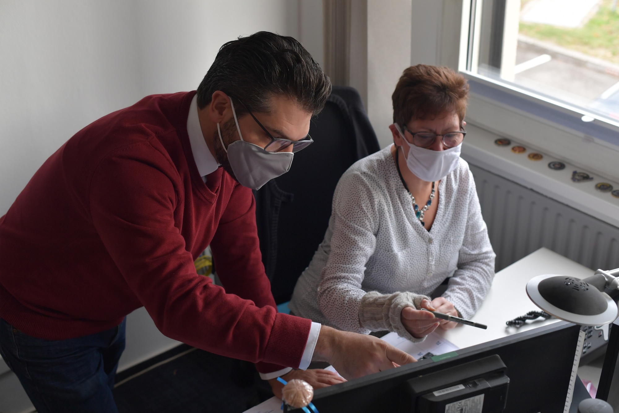 A man and woman pointing at a computer monitor.