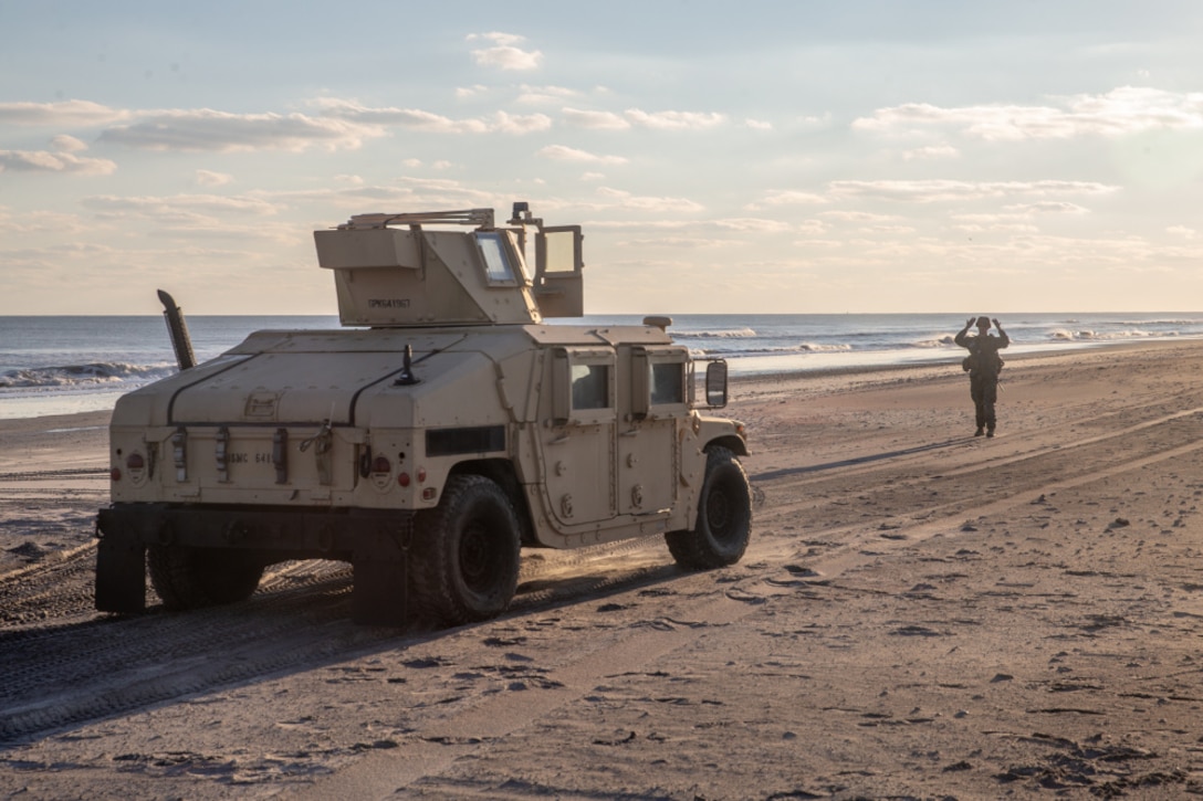 A U.S. Marine with Combat Logistics Battalion 6, 6th Marine Regiment, directs a vehicle on where to position itself on Camp Lejeune, North Carolina, Dec. 5, 2020. This ship-to-shore exercise simulated tactical offloading in a beach setting while utilizing LCAC support to rapidly evacuate the area or establish a command operations center. (U.S. Marine Corps photo by Lance Cpl. Chase W. Drayer)