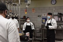Jorge Busso, Elkhorn Dining Facility executive chef and manager, leads a team of chefs in a briefing before the start of the lunch hour, Dec. 1, 2020, at Malmstrom Air Force Base, Mont. Busso is in charge of planning and executing holiday meals with the help of contractors and food service Airmen. (U.S. Air Force photo by Airman Elijah Van Zandt)