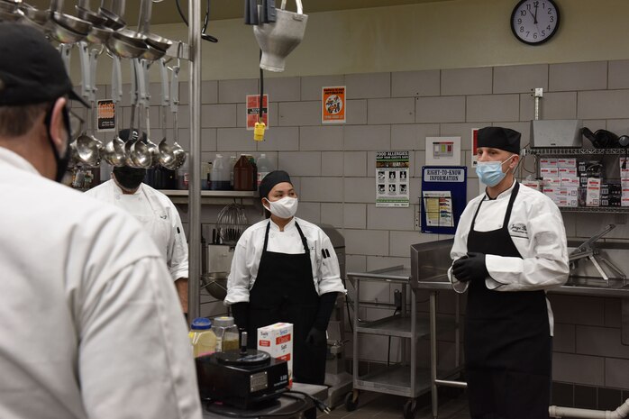 Jorge Busso, Elkhorn Dining Facility executive chef and manager, leads a team of chefs in a briefing before the start of the lunch hour, Dec. 1, 2020, at Malmstrom Air Force Base, Mont. Busso is in charge of planning and executing holiday meals with the help of contractors and food service Airmen. (U.S. Air Force photo by Airman Elijah Van Zandt)