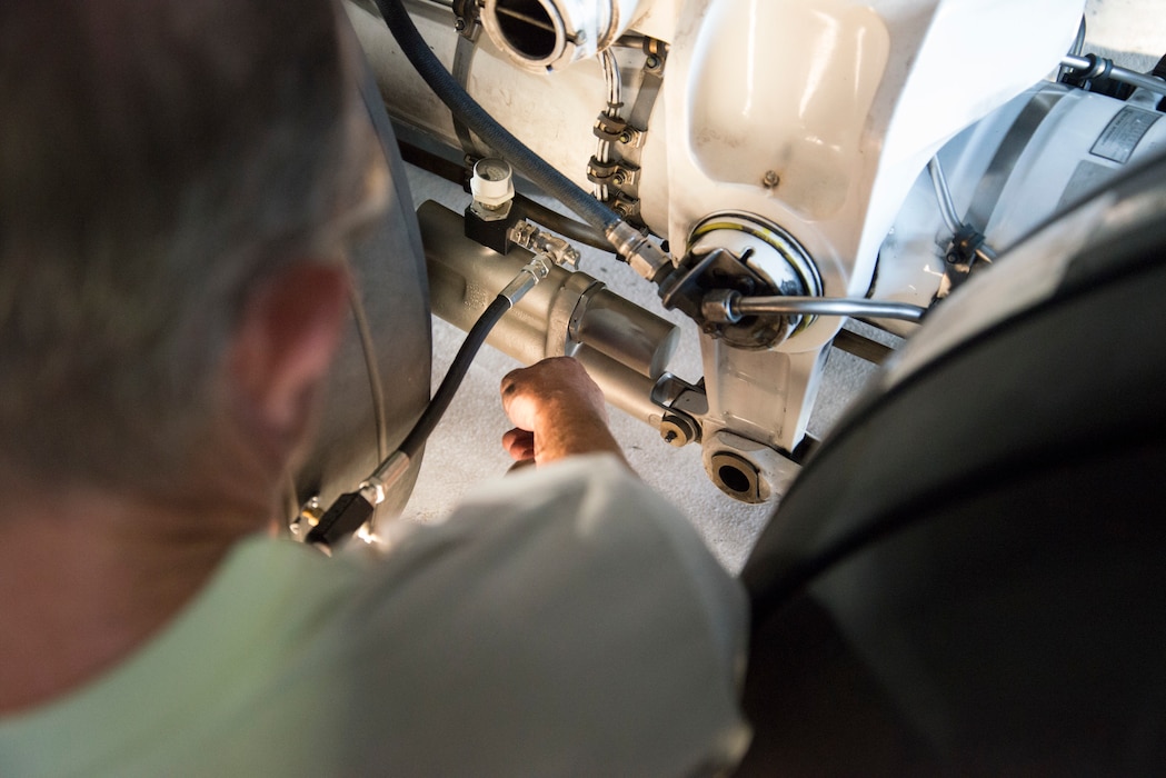 An Airman's hand enters the frame, holding an instrument to measure pressure.