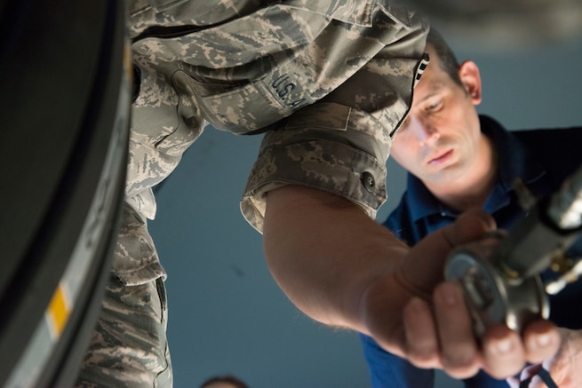 An Airman's hand enters the frame, holding an instrument to measure pressure.