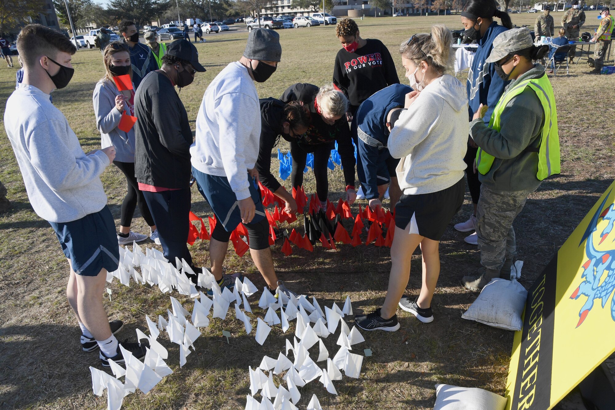 Members of the 81st Contracting Squadron place flags inside the letters, KAFB, at Heritage Field during the Dragon March at Keesler Air Force Base, Mississippi, Dec. 8, 2020. The theme of the three-mile walk was "Stronger Together." (U.S. Air Force photo by Kemberly Groue)