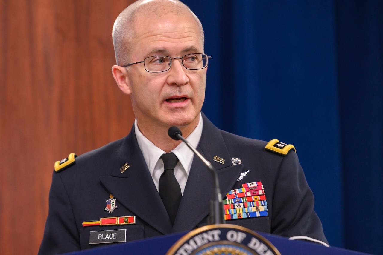 A man in a military uniform standing at a lectern with a microphone speaks