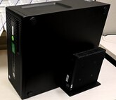 Photo of A large black computer tower sits alongside a much smaller black box called a Thin Client device.