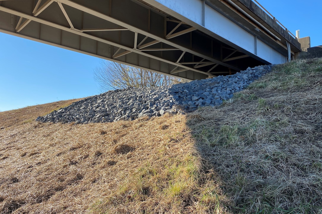 underside of highway bridge, embankment covered in rock