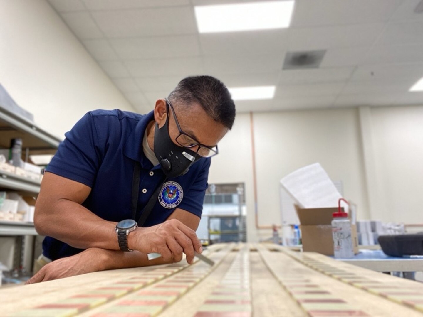 A man leans over a table to inspect a product