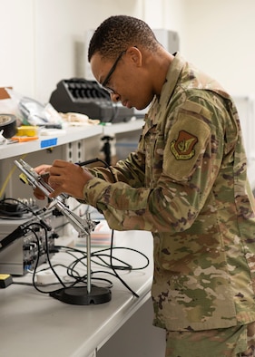 Airman 1st Class Samuel Wambuzi, 36th Maintenance Squadron aircraft, electrical and environmental journeyman, uses a soldering iron to melt pieces and reattach new solder to fix the circuit board at Andersen Air Force Base, Guam, Dec. 3, 2020. Wambuzi is one of the five Airmen that work on the Air Force Repair Enhancement Program here, fixing technology and equipment across the base, saving and making the 36th Wing thousands yearly. (U.S. Air Force photo by Senior Airman Aubree Owens)
