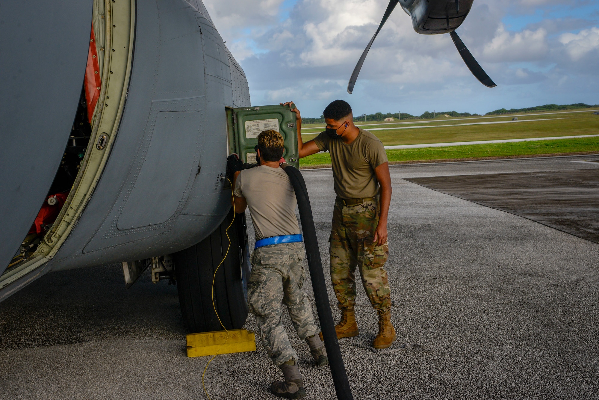 Senior Airman Stephen Yarbrough (left), 374th Aircraft Maintenance Squadron crew chief out of Yokota Air Base, Japan, and Airman 1st Class Andre Anderson, 36th Logistics Readiness Squadron fuel distribution operator, attaches a fuel hose to C-130J Super Hercules during Operation Christmas Drop 2020 at Andersen Air Force Base, Guam, Dec. 9.